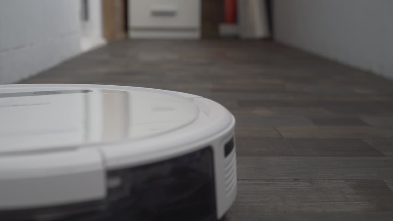 el robot aspirador automático se mueve a lo largo de su trayectoria. robot aspirador limpieza automática en el hogar. casa inteligente. moderno aspirador robótico limpia el piso. toma de primer plano. tecnologías modernas