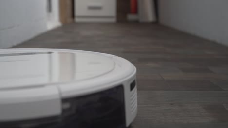 the automatic robot vacuum cleaner moves along its trajectory. vacuum robot auto cleaning at home. smart house. modern robotic vacuum cleaner cleans the floor. close up shot. modern technologies