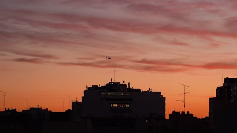 helicopter against colorful sunset sky over city