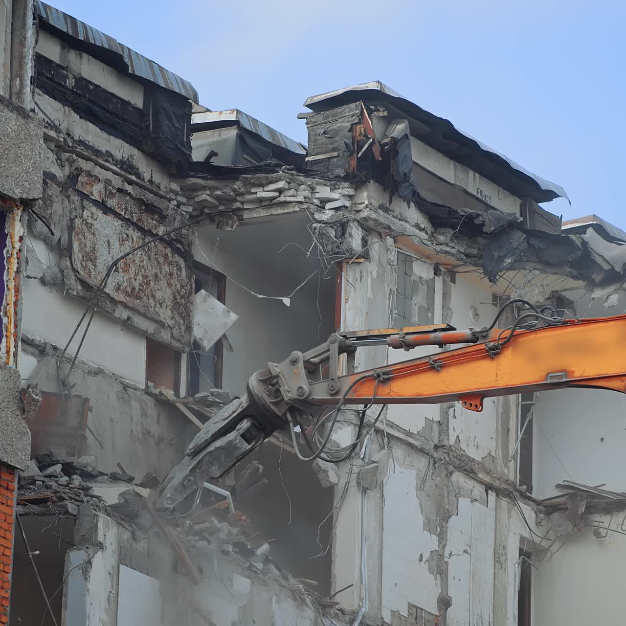 Powerful excavator claw dump the debris on the ground. Deconstruction site covering with the dust. Clear blue sky at the backdrop