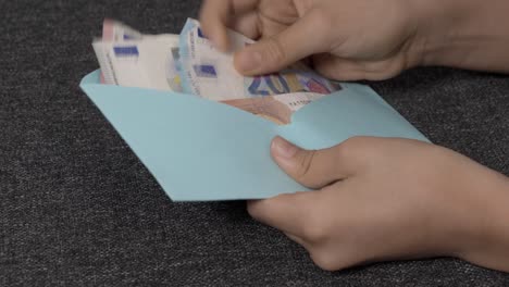 teenage boy hands open blue envelope, checking, counting a few cash euro banknotes. present gift, saving, financial literacy for children