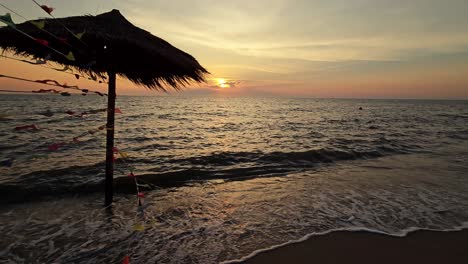 silueta de atractivo el paraguas de paja en el mar y saludando al barco en el horizonte al atardecer