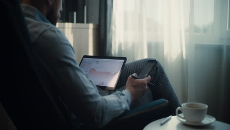 close up of financial expert working on smartphone, monitoring real-time stocks and exchange market charts, making investments. successful businessman works in comfortable office of investment bank.