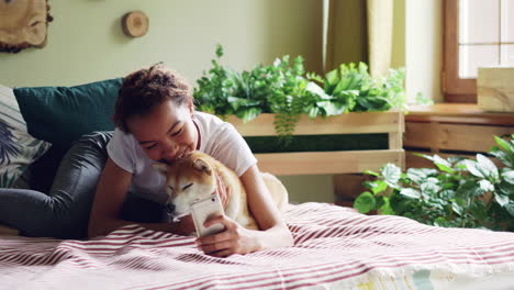 teenage girl and dog on bed using phone