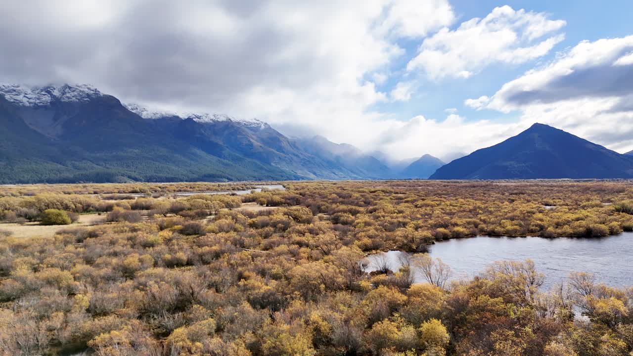 Aerial footage captures Glenorchy's vast, colorful landscape with mountains, clouds, and reflective water under dynamic lighting