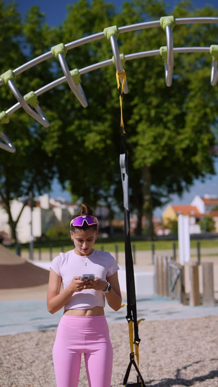 Woman using phone at outdoor workout station
