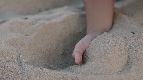 a child takes sand in his hand and lets it run between his fingers