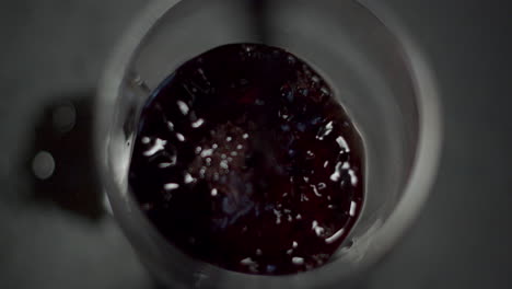 de arriba hacia abajo de vino tinto que se derrama en el vaso y se derrama sobre la mesa
