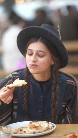 young woman eating pizza outdoors