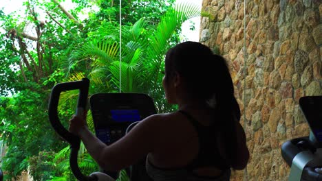 profile shot of brunette long hair asian young woman in sport clothes walking in treadmill and smiling at gym in luxury resort hotel at daytime
