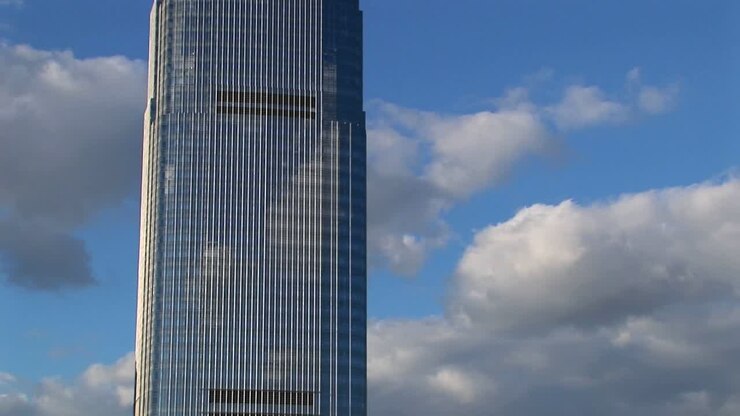 Um timelapse de nuvens se movendo através de um céu azul atrás de um arranha-céu alto e reflexivo em Hoboken, Nova Jersey