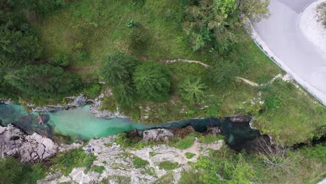 a drone speeds sideways high above a rocky gorge, looking straight down to unveil crystal-clear waters, rugged terrain, and the wider scenic wilderness of the surrounding forest