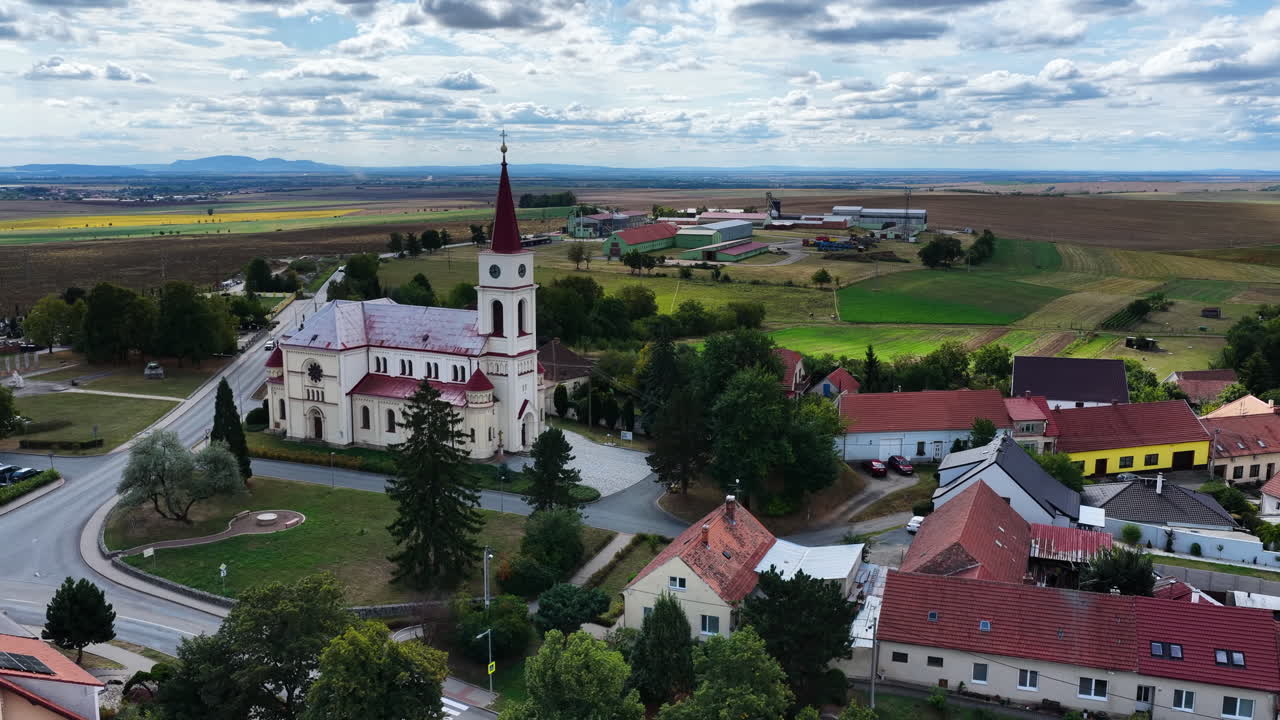 Filmisk flygdrönarbild över bykyrkan och landsbygden i Blížkovice i regionen södra Mähren i Tjeckien omgiven av jordbruksmark