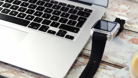 coffee cup, laptop, smart watch on wooden plank