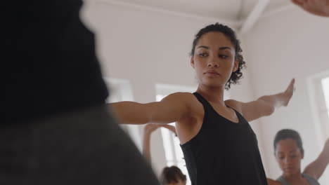 beautiful mixed race yoga woman practicing warrior pose meditation with group of multiracial women enjoying healthy lifestyle exercising in fitness studio at sunrise