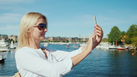 Eine-Frau-Benutzt-Ein-Smartphone-Auf-Einer-Brücke-Mit-Blick-Auf-Stockholm-Schweden