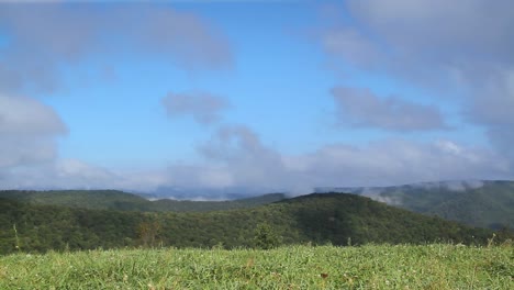 Lapso-De-Tiempo-De-Nubes-Hinchadas-Blancas-Moviéndose-A-Través-Del-Cielo-Y-Las-Montañas