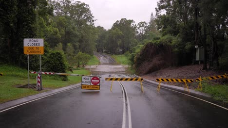 gold coast, queensland, 16 de febrero de 2024 - fotografía amplia de la señalización de cierre de carreteras con inundaciones a través de la carretera de hardy en mudgeeraba después de que las fuertes lluvias continúen azotando el sureste de queensland, australia