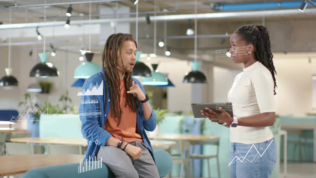 Woman tilting tablet causing animated charts between them, seated man explaining business metrics