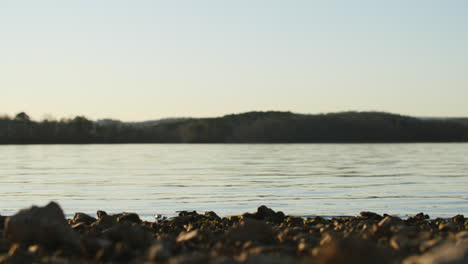 wide shot of a lake with the mountains and colors of the sunset in the sky in the background.
