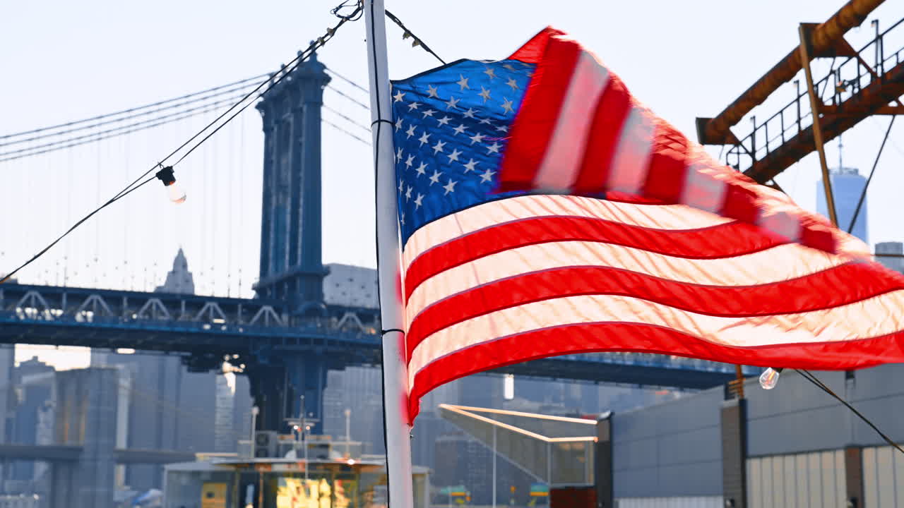 Albero della barca con bandiera americana che sventola nel vento. Il Manhattan Bridge sullo sfondo