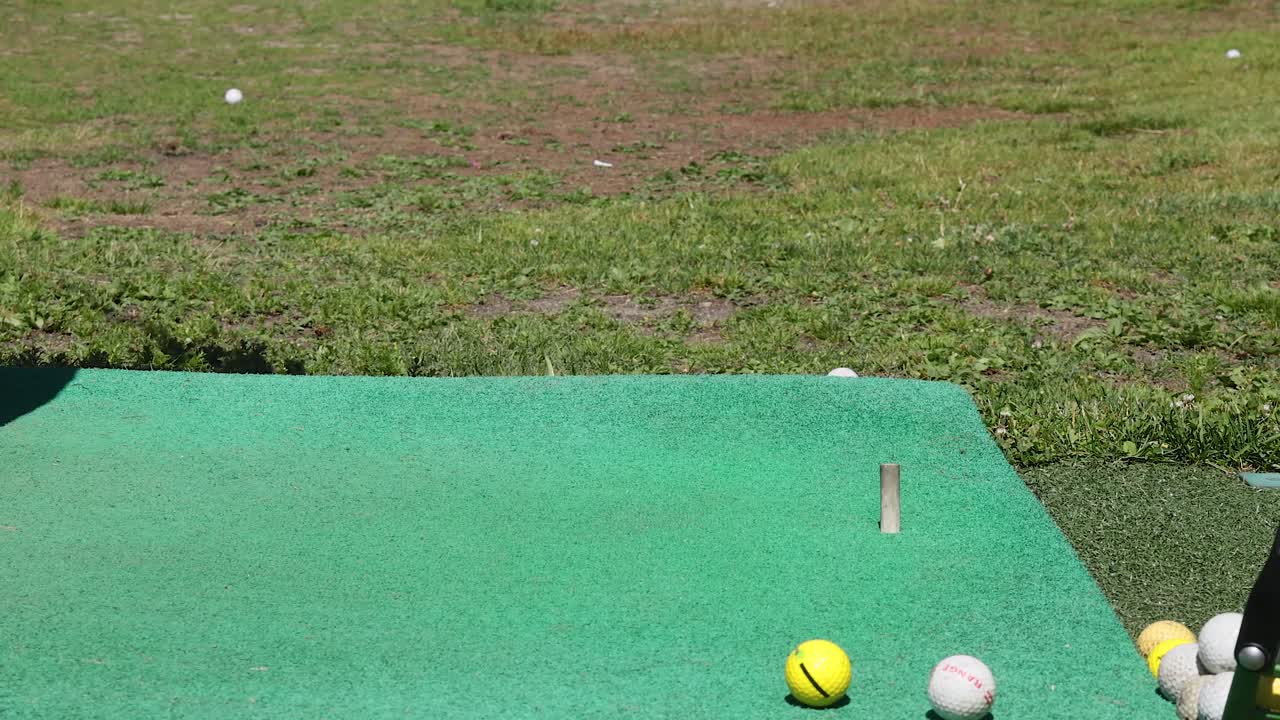 연습 매트에서 골프 클럽으로 공을 때리는 것