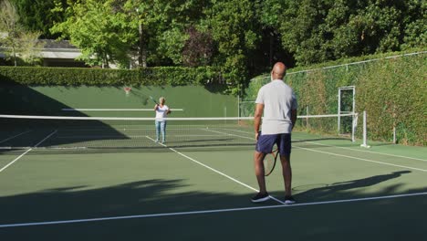 pareja de mayores afroamericanos jugando al tenis en la cancha de tenis en un brillante día soleado