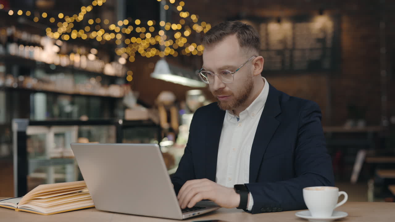 Человек работает на ноутбуке в кафе.