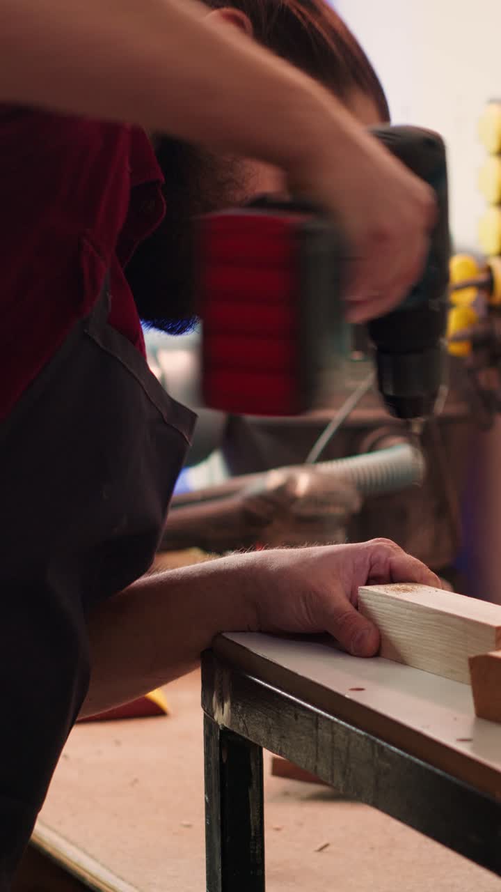 Man Drilling Hole into Wood with Power Drill in Workshop