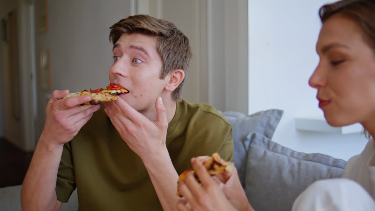 Cheerful guy talking girlfriend at domestic atmosphere closeup. Pair eating