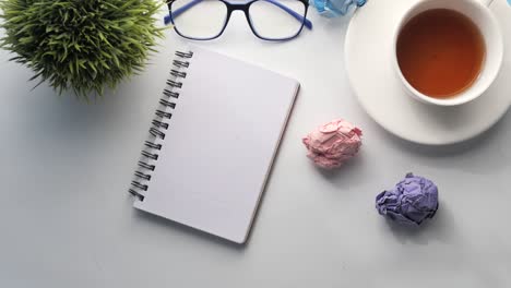 simple desk setup with notebook, tea, and glasses