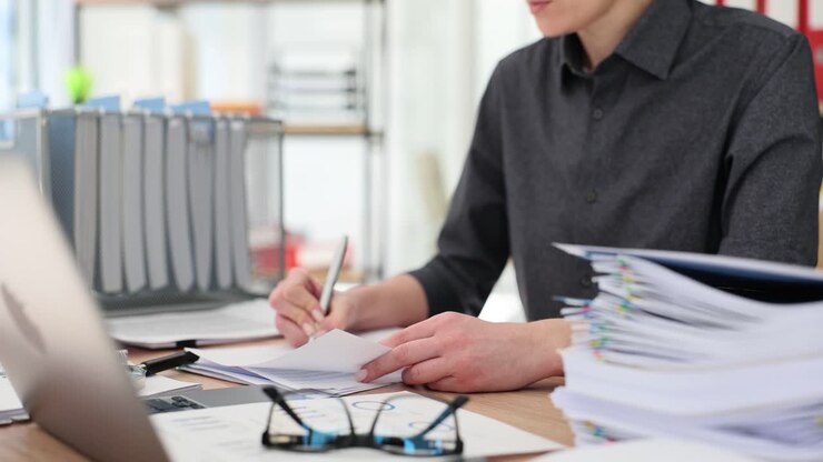 Person working in an office with documents and a laptop