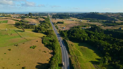 Aerial-shot-of-Chiloé's-rolling-hills-and-a-winding-road-at-sunset