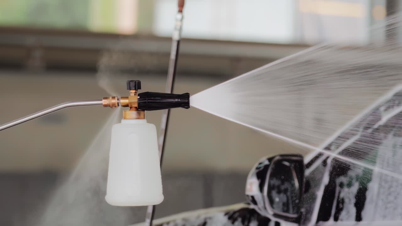 스프레이어는 스로우 모션으로 반이는 자동차 표면에 직접 거품 비누를 스프레이합니다.