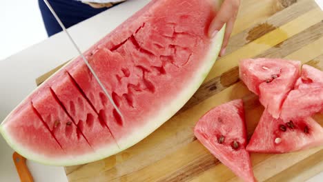 sección media de una mujer cortando frutas en una tabla de cortar contra un fondo blanco