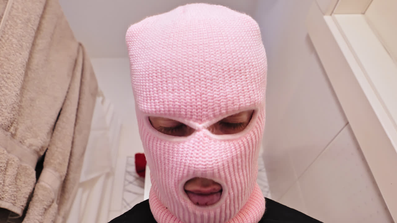 Tight close up of man wearing soft pink balaclava in Soviet-era bathroom