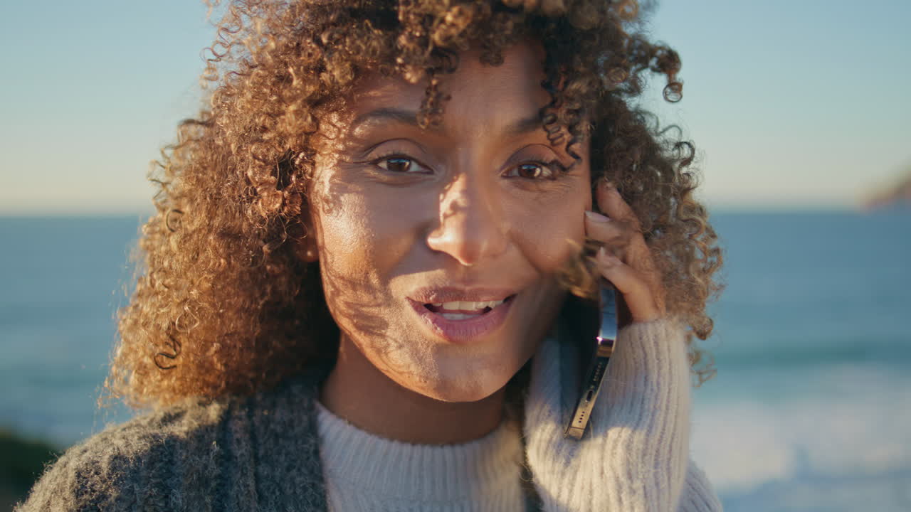 Relaxed woman talking mobile phone on beach closeup. Happy girl looking camera
