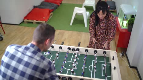 diverse coworkers playing foosball during break