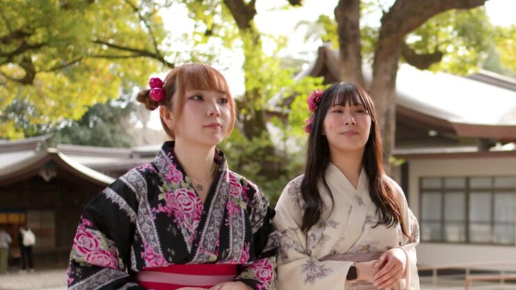 Due donne giapponesi che indossano kimono floreali tradizionali parlano e ridono all'aperto in un santuario shintoista