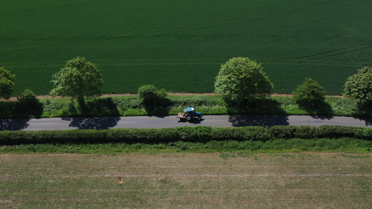 길을 운전하는 작은 파란색 트랙터의 공중 샷