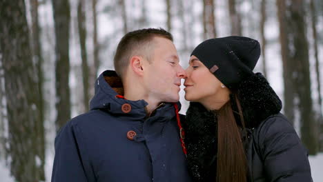 close-up of a man and a woman in love standing in the winter forest hugging each other and looking into the distance