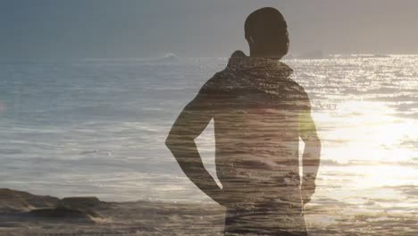 animation of seascape over exercising african american man taking a break, stretching