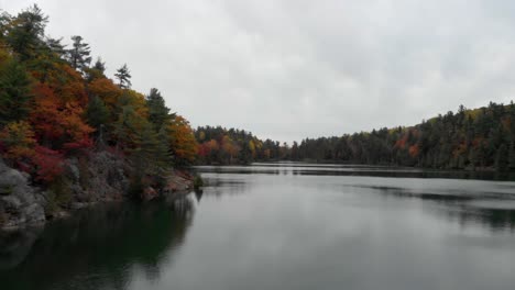 Tomas-Aéreas-Bajas-Sobre-El-Lago-Rosa-En-Gatineau-Quebec-Dando-La-Vuelta-A-La-Esquina-De-Una-Colina-Que-Conduce-Al-Agua-Y-Va-De-Un-Extremo-Al-Otro-Del-Lago