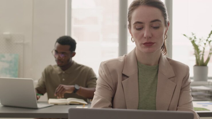 Vista ravvicinata di una donna che usa un laptop seduta al tavolo in ufficio