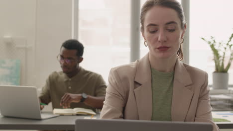 Vista-De-Cerca-De-Una-Mujer-Usando-Una-Laptop-Sentada-A-La-Mesa-En-La-Oficina