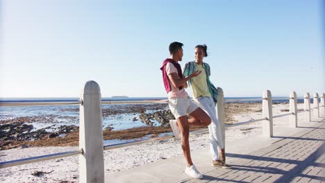 happy diverse gay male couple talking at promenade by the sea, slow motion