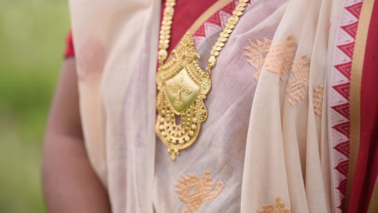 Indian woman wearing a gold necklace of a human face of Goddess Durga, close up