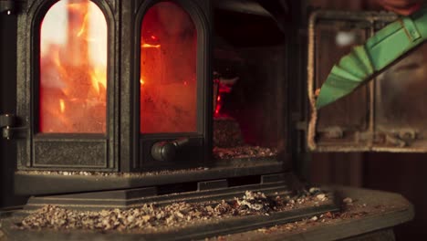 opening door of an antique wood burning stove to throw in sawdust in the house