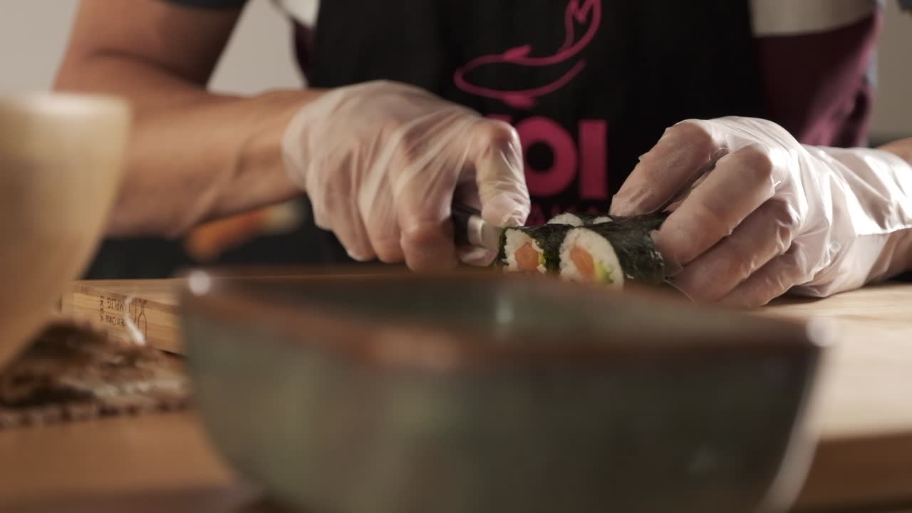 el chef cortando rollos de sushi en la cocina