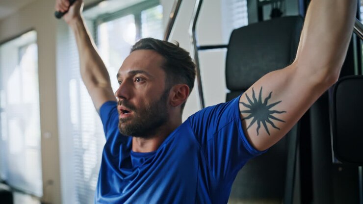 Man pumping biceps machine for workout closeup. Strong sportsman training at gym